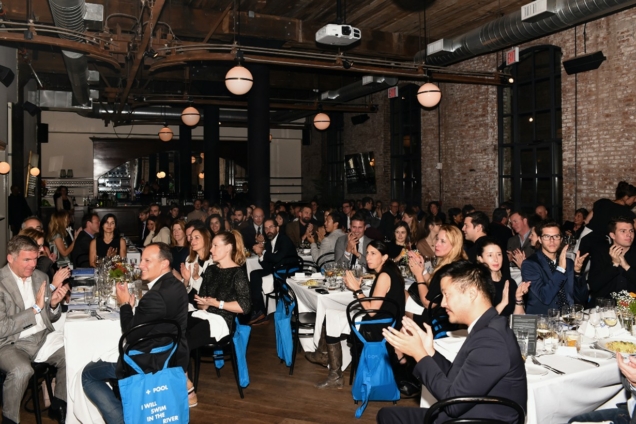 people applauding while seated at tables in a venue