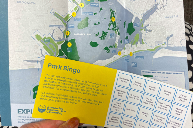 Hand holding a redesigned paper map of Jamaica Bay-Rockaways region and a Bingo Card