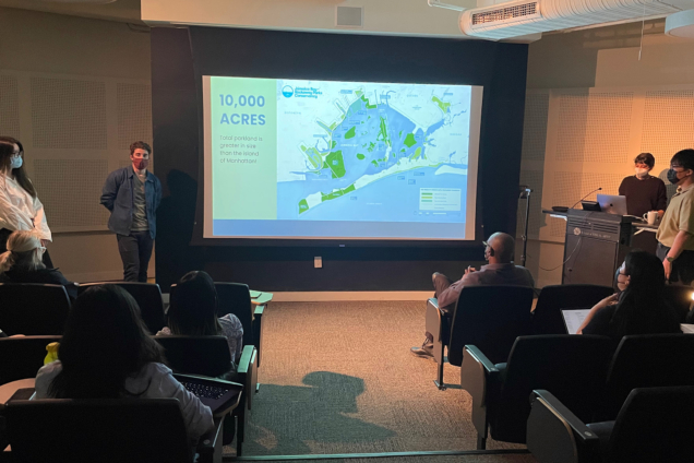 Four students standing in front of a screen displaying a map.